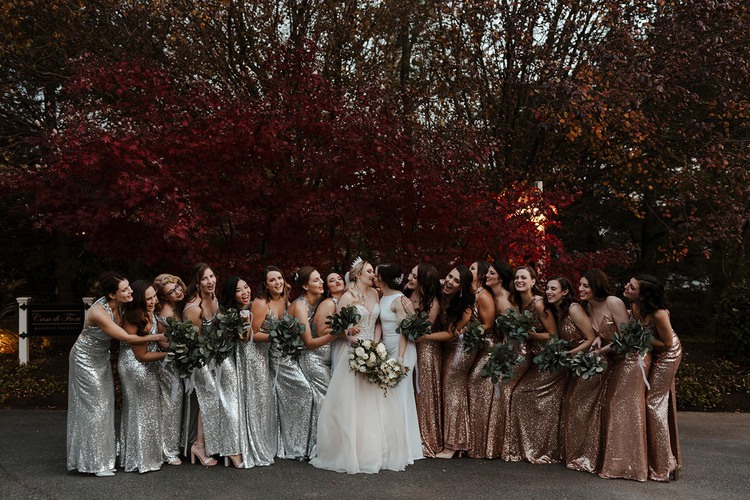 Brides kissing surrounded by wedding party